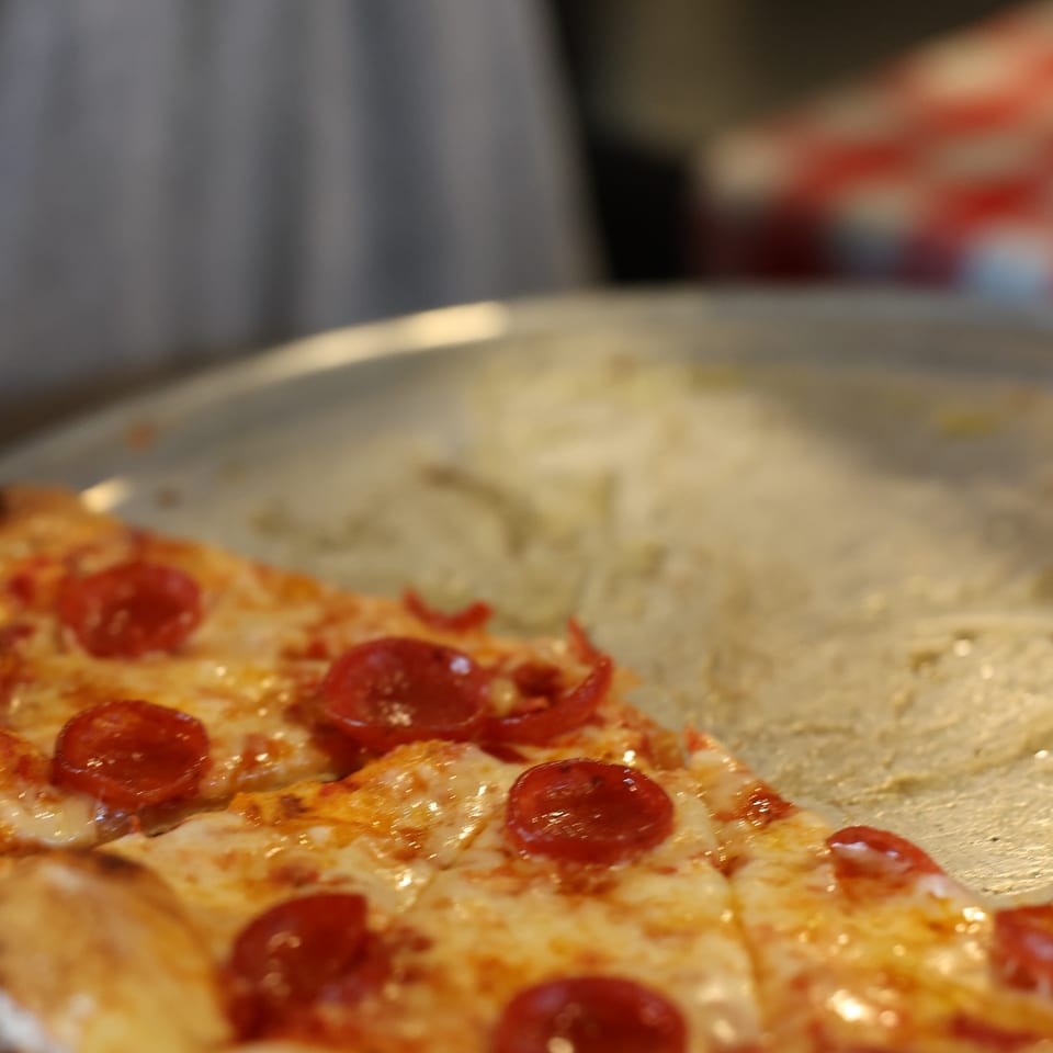 Close-up of a pepperoni pizza with melted cheese and a golden crust on a plate.